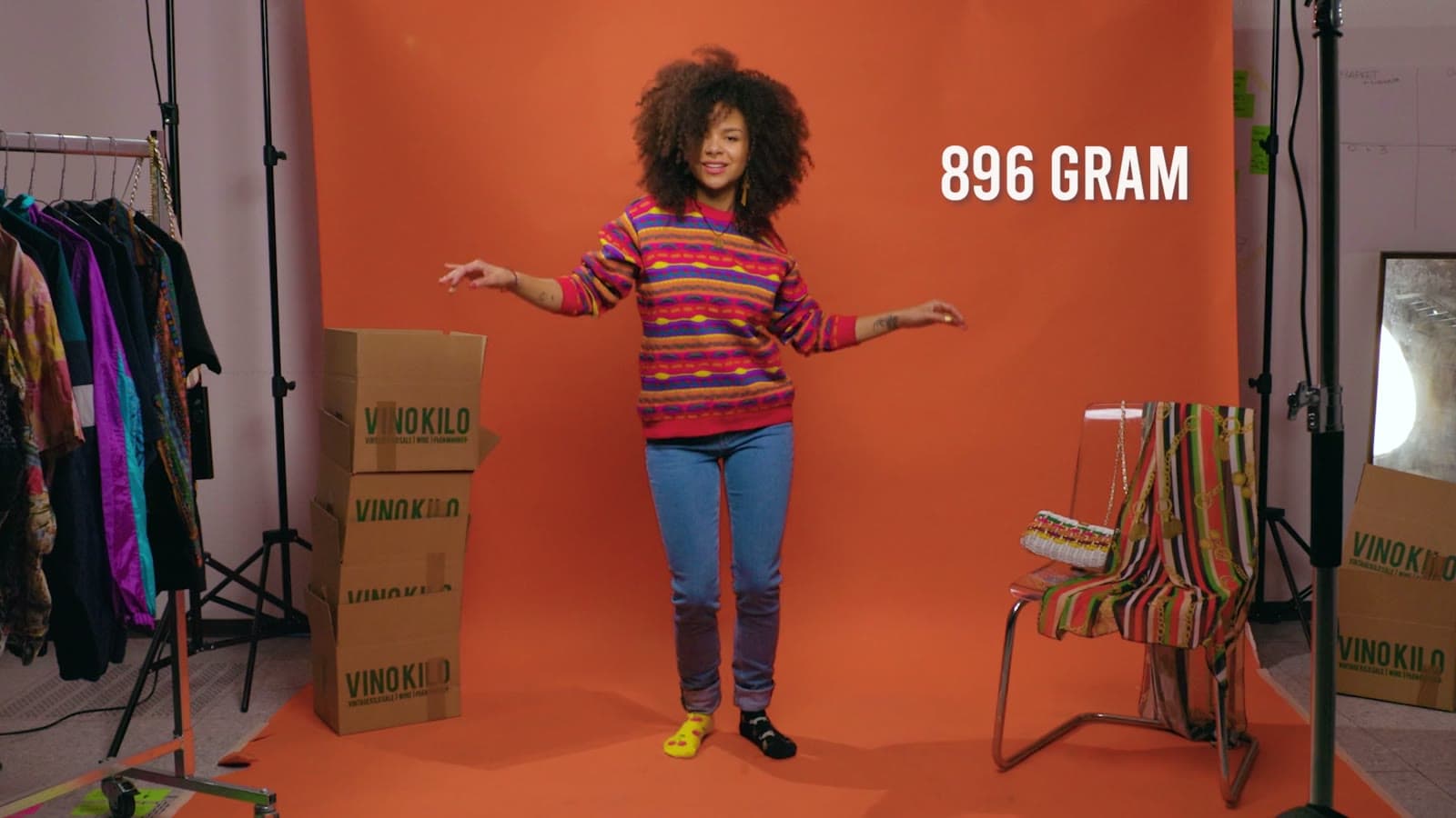 Model voor een oranje achtergrond, met het gewicht van haar outfit in beeld