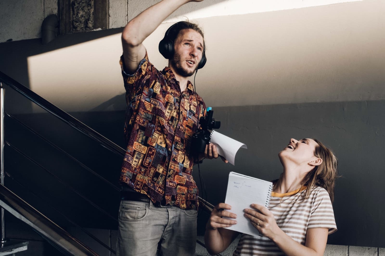 Jonathan met koptelefoon geeft aanwijzingen op de set, een collega lacht