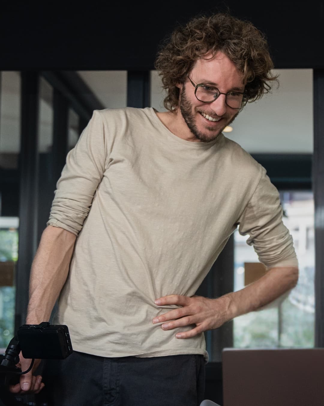 Jonathan kijkt lachend naar zijn laptop, met een camera in zijn hand